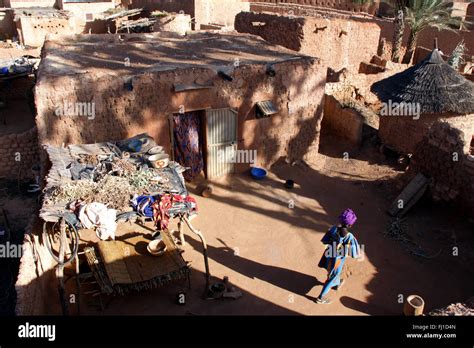 A Woman Stands In The Courtyard Of A Traditional Mud Banco House In The