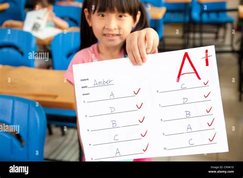 Smiling Little Girl Showing Exam Paper With A Plus In The Classroom