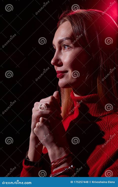 portrait of elegant woman with long hair in red sweater and dark background with red light