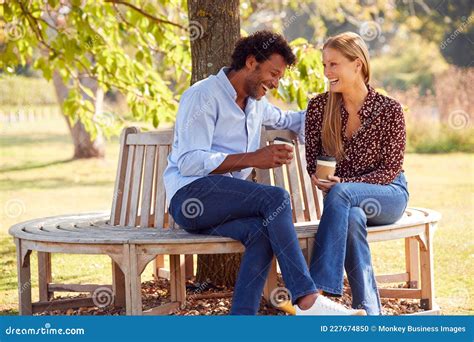 Loving Mature Couple Relaxing Sitting Together On Bench Under Tree In Summer Park With Coffee