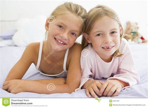 Zwei Junge Mädchen In Ihren Pyjamas Die Auf Einem Bett Liegen Stockbild Bild Von Lügen