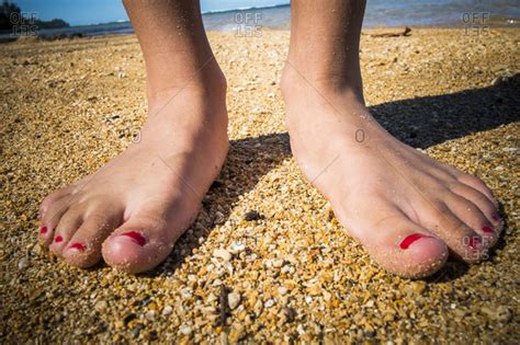 Close Up Of The Feet Of A Teenager On The Beach Stock
