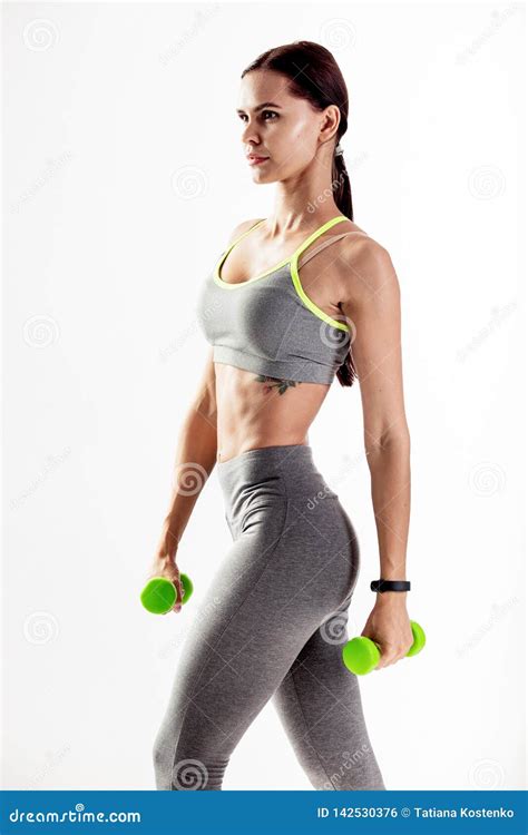 Slim Woman Dressed In A Gray Sportswear Is Doing Exercises With