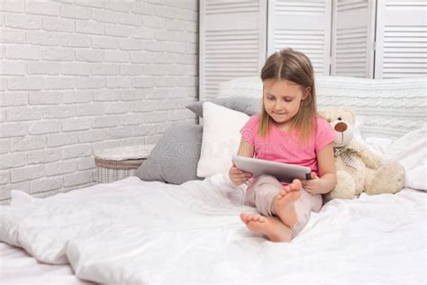 Cute Little Girl Lies In Bed Uses Digital Tablet Stock Photo Image