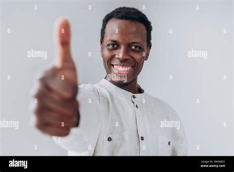 Happy African American Blurry Person In White Shirt Shows Thumb Up Gesture Posing For Camera On