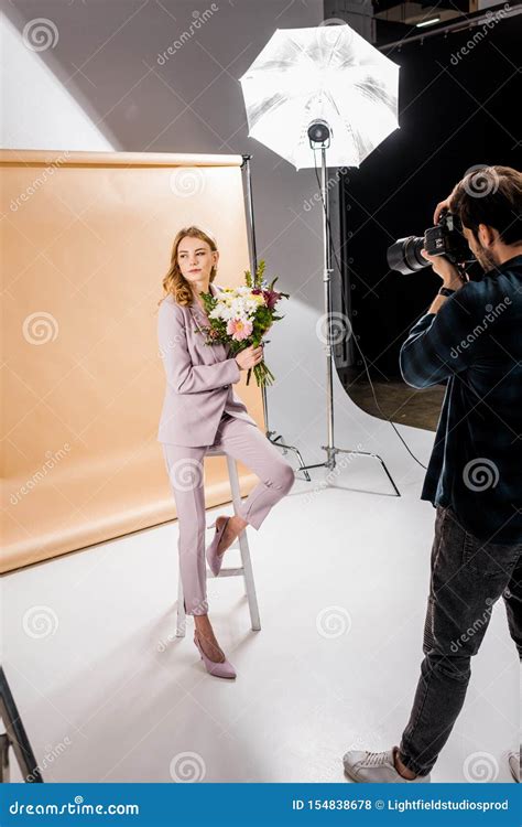 Photographer Shooting Attractive Young Female Model Posing With Flowers