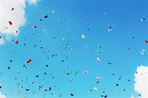 Drops Of Multicolored Confetti On The Blue Sky Background Stock Photo