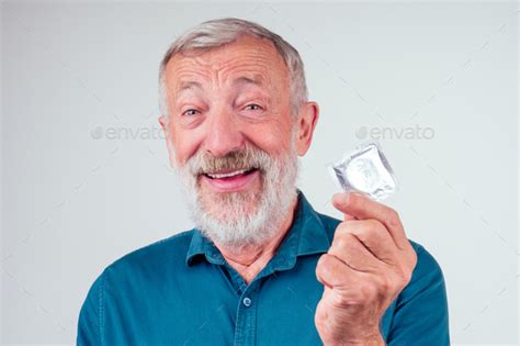 Caucasian Old Senior Man Holding Packed Rubber Latex Condom In Studio