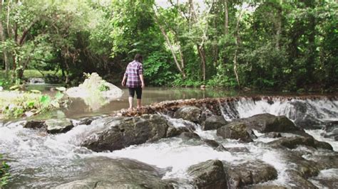 低角度的年轻女子赤脚走下瀑布的水流。女性游客在热带雨林中享受自然，自由和积极的生活理念。亚洲 泰国视频素材 id vcg42n1170840043 vcg