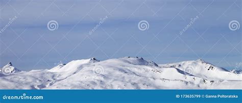 High Mountains With Snowy Slopes And Sunlit Cloudy Sky At Winter