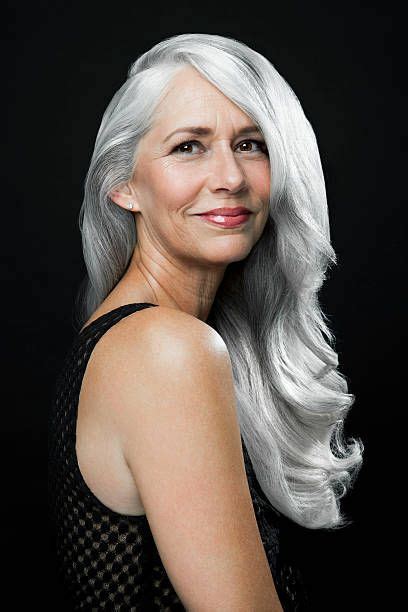 portrait of a woman with long wavy silver gray hair looking over long gray hair grey
