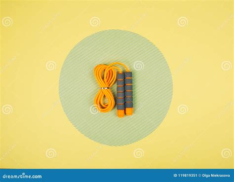 Orange Jump Rope Or Skipping Rope On Yellow And Green Background Stock