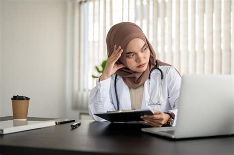 Напряженная и серьезная азиатская мусульманка врач смотрит в окно с задумчивым лицом Премиум Фото