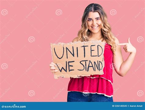 Young Caucasian Woman Holding United We Stand Banner Pointing Finger To