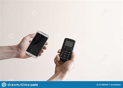 A Person Hands Holding Two Cell Phones Vintage Old And Modern New Era
