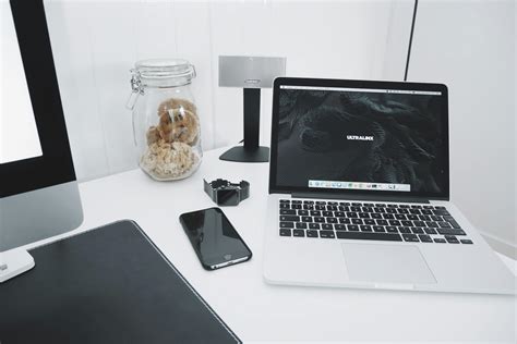 Macbook Pro With Black Screen Beside Notebook On Brown Wooden Table