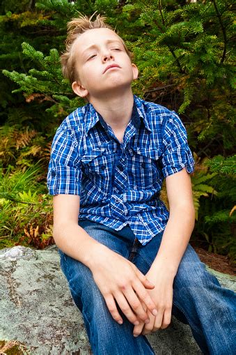 Young Boy Contemplates While Sitting In The Woods Stock
