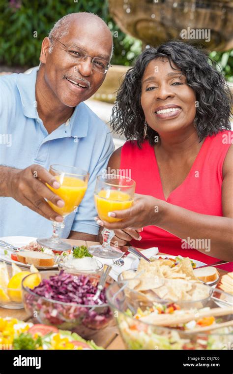 Happy Smiling Man And Woman Senior African American Couple Drinking Orange Juice And Eating Healthy