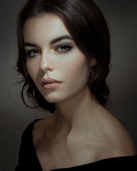 A Woman With Dark Hair And Blue Eyes Is Posing For A Photo In The Dark