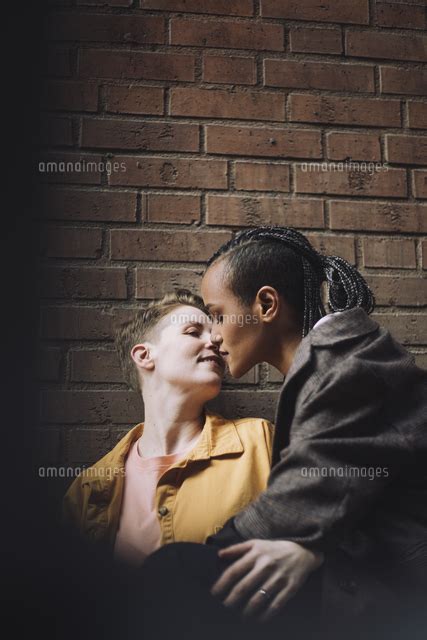 Affectionate Lesbian Couple Embracing Each Other By Brick Wall[11081047271]の写真素材・イラスト素材｜アマナイメージズ