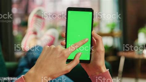 Feminine Hand Scrolling Feed On Smartphone With Green Screen Mock Up