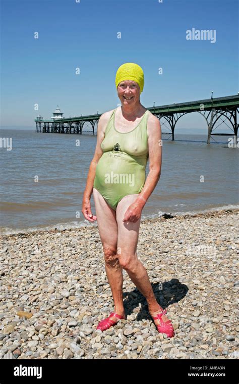 Old Lady In Bathing Costume And Swimming Hat On Pebbled Beach In Ffront