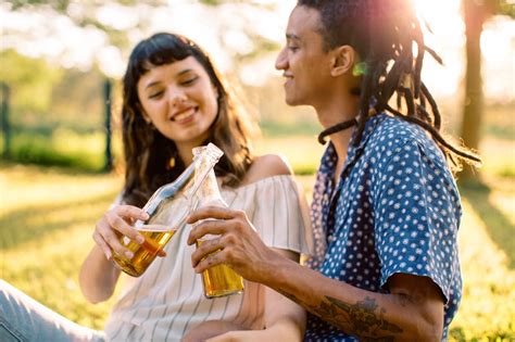 Romantisches junges gemischtrassiges Paar stößt fröhlich mit Bierflaschen auf ein Date an Zwei