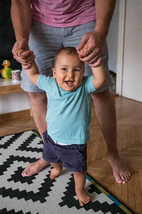 Baby Taking His First Steps With Dad By Stocksy Contributor