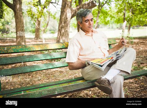 Man Sitting On A Park Bench And Reading A Newspaper Lodi Gardens New
