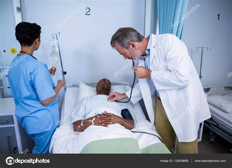 Doctor Checking Patient Heartbeat With Stethoscope In Ward Stock Photo