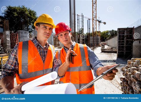 Architect And Structural Engineer Dressed In Orange Work Vests And