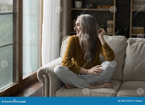 Happy Pretty Mature Grey Haired Woman Resting On Cozy Sofa Stock Image