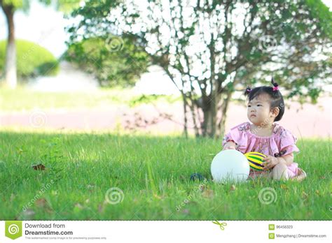 Carefree Chinese Baby Girl Play A Ball And Balloon On The Lawn Stock