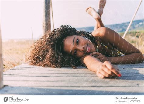 Schöne junge schwarze Frau in einer hölzernen Fußgängerbrücke am Strand liegt ein