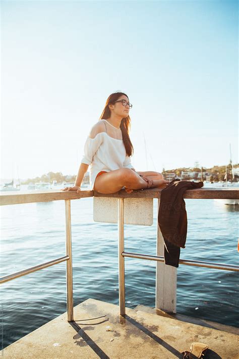 Girl Sitting On Pier Railing By Stocksy Contributor Maximilian Guy