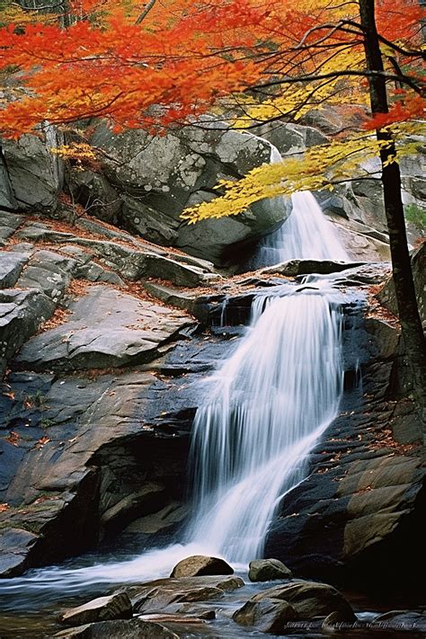 A Waterfall With Red Leaves And A Rocky Bank And Rock Mountain