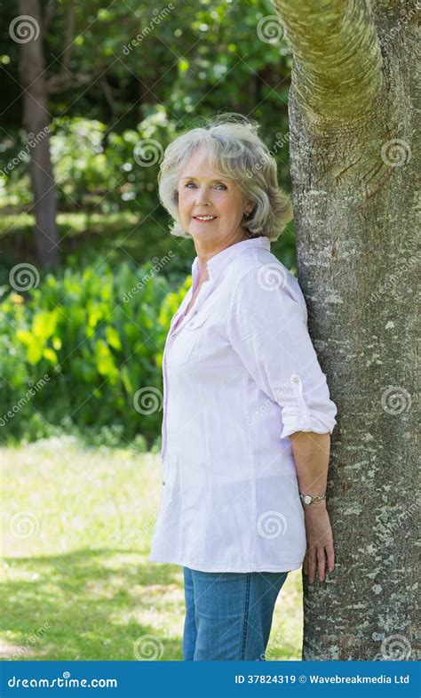 Portrait Of A Mature Woman Leaning Against Tree Trunk Stock Image