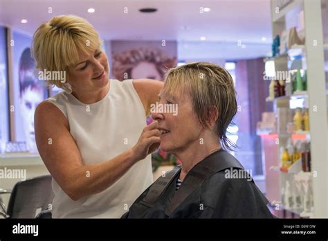 Older Woman In Hair Salon Having Hair Cut And Styled By