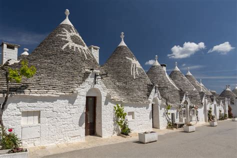 Row Of Traditional Whitewashed Trulli Houses With Conical Roofs In