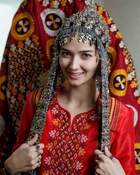 A Woman Wearing A Red Dress And Headdress Smiles At The Camera With Her