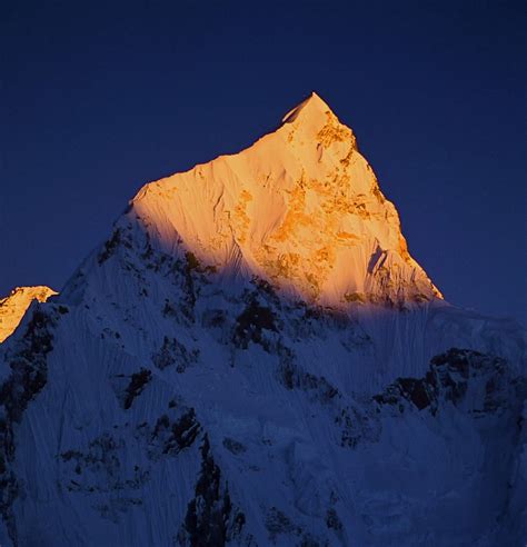 The Top Of A Snow Covered Mountain At Night With Bright Light On Its Face