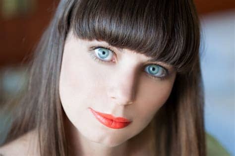 Smiling young woman putting on her lip makeup. Blue-Eyed Folks, Beware: You May Be At Higher Risk Of Melanoma