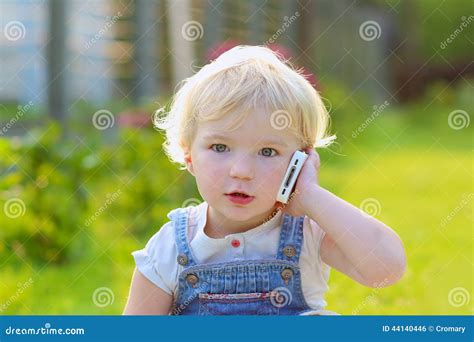 Cute Toddler Girl Talking With Mobile Phone Outdoors Stock Photo