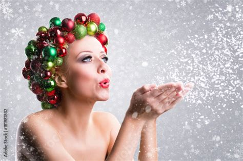 Weihnachtlich geschmückte Frau pustet Schnee Stockfotos und