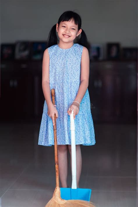 Smile Asian Little Girl Sweeping With Broom And Dustpan In The House