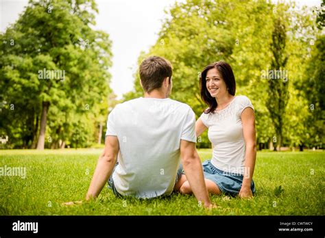 Young Happy Couple Talking Together Outdoor Sitting On Grass Stock