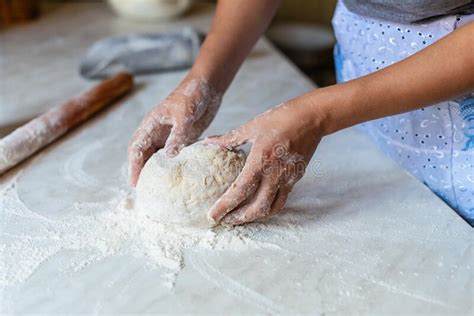 Hands Of A Young Woman Kneading Dough To Make Bread Or Pizza At Home