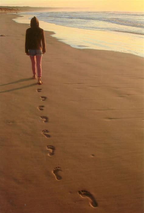 A Person Walking On The Beach With Footprints In The