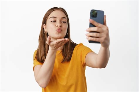 free photo beautiful girl taking selfie video chat on mobile phone sending air kiss at