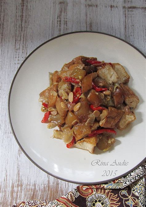 Oseng kikil sapi tahu cabe ijo is traditional indonesian food made from beef skin or tendon and tofu with spicy seasoning served with traditional clay plate on wooden table. Tahu Kikil Masak Tauco - DapurManis